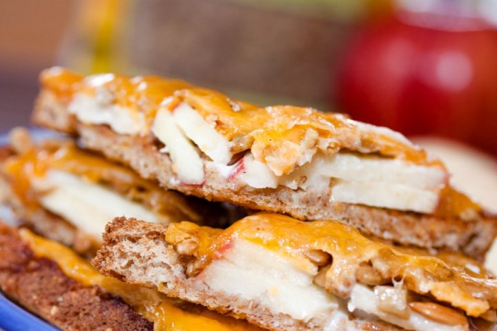 Open-faced Apple Cheddar Melt Sandwich with bread, mayo, apple slices, sunflower seeds, and cheddar melted on top and text Apple Cheddar Melt: Add Salt & Serve